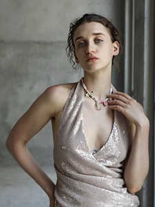 Detail of bohemian sun pendant necklace with shell and flower elements worn by a model