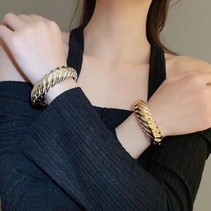 Detailed view of chunky spiral textured open bangles in gold and silver finish