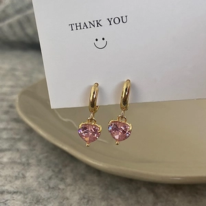 Detail of gold heart earrings with pink zircon stone on a white thank you card