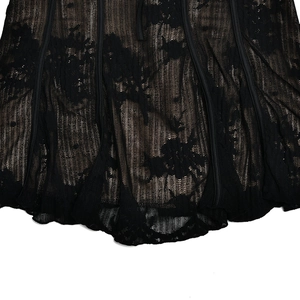 Détail de l'ourlet en dentelle noire avec motifs floraux et doublure beige du vêtement
