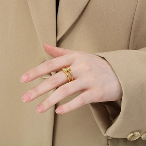 Close-up of gold knot ring with micro-pave crystals worn on hand over beige suit fabric
