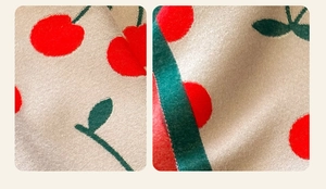 Detailed knit texture of cashmere-like scarf with red cherry and green leaf patterns