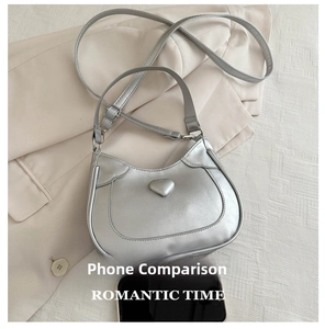 Comparison showing the small size of the silver heart crescent bag next to a smartphone