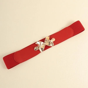Macro detail of red elastic waist belt featuring a polished gold metallic bow buckle