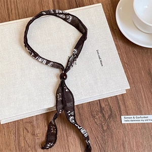 Dettaglio della collana vintage in tessuto paisley con perla di legno rossa