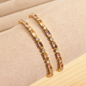 Dettaglio di bracciali dorati con cristalli rosa e trasparenti su espositore gioielli
