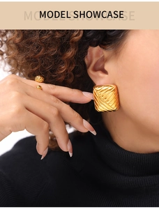Détail de boucles d'oreilles carrées dorées avec texture tissée sur modèle