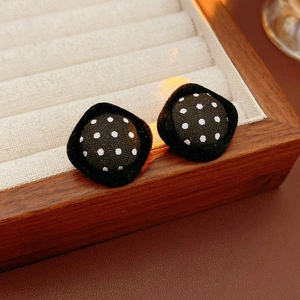 Close-up of fabric polka dot square stud earrings on a wooden jewelry tray display