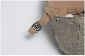 Detail of adjustable metal buckle and silver snap button on cotton beret fabric