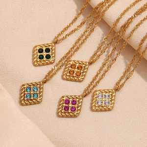 Detail view of colorful diamond-shaped pendants on gold twisted chains over silk fabric