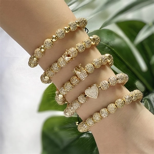 Close-up of gold beaded bracelet set with micro-pave zircon crown and heart charms