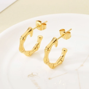 Macro view of gold bamboo texture earrings on a white porcelain plate