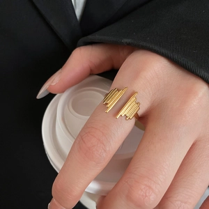 Polished gold heart cutout ring on a model's finger with minimalist professional styling