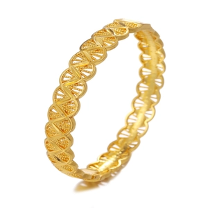 Detailed close-up of golden lace-style hollow pattern on a metal bridal wedding bangle
