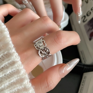 Nahaufnahme eines silbernen Rosenblütenrings mit Reliefdetails an einem Finger