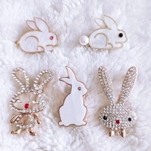 Detailed close-up of rabbit brooches with rhinestones and pearls on white fur background