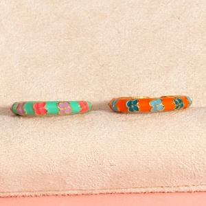 Macro shot of colorful enamel flower rings with gold plating on beige velvet background