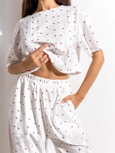 Détail de l'ensemble de détente blanc à motifs de cœurs rouges et tissu ajouré à manches