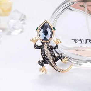 Elegant lizard brooch with sparkling crystals and golden accents in a luxury setting