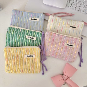Close-up of five colorful knitted cosmetic bags with textured fabric and wrist straps