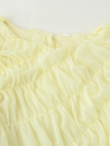 Detail of yellow chiffon dress showing elegant pleated texture and smocked bodice craftsmanship