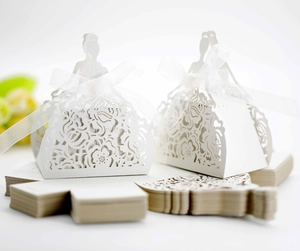 Detail of white laser-cut wedding candy boxes in bridal gown shape with silk ribbons