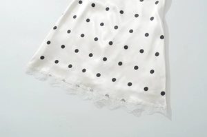 Detailed view of the black polka dot satin hem with elegant white lace trim