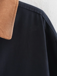 Detailed close-up of brown corduroy collar on dark blue cotton canvas jacket
