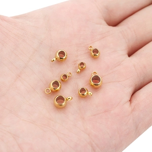 Macro shot of 18k gold-plated stainless steel jewelry beads with loops on a hand