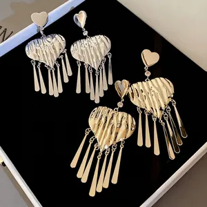 Hammered heart tassel earrings in gold and silver finish on black velvet display