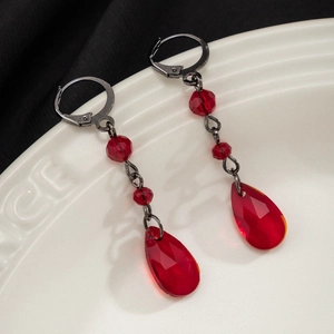 Detailed macro view of red teardrop crystal earrings with gothic black lever-back hooks