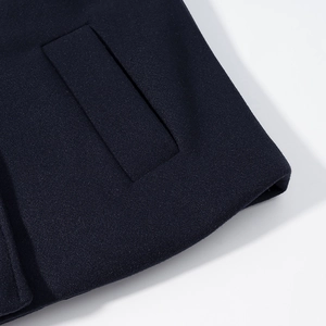 Close-up of navy blue wool blend fabric showing pocket and cuff detail on jacket
