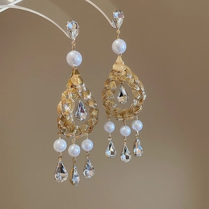 Close-up of vintage hollow drop earrings with pearls and crystal drops in gold finish
