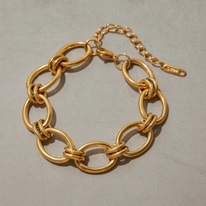 Gros plan d'un bracelet à grosses mailles dorées en acier inoxydable avec fermoir mousqueton