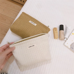 Detail of tweed makeup bags in khaki and cream with simple wish woven labels
