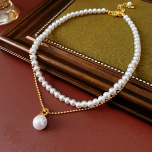 Detail of layered gold-plated necklace featuring elegant white pearls on vintage wood