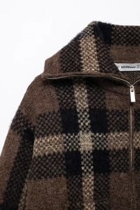 Dettaglio della maglia soffice e della zip argentata sulla giacca a quadri rombi