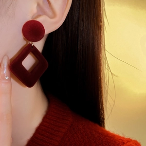 Détail de boucles d'oreilles géométriques rouges avec éléments ronds et carrés