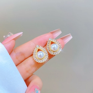 Close-up of golden teardrop pearl earrings with shimmering cubic zirconia accents