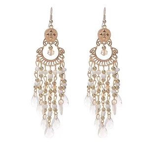 Detail of bohemian gold-plated tassel earrings with white beads and crystal teardrop pendants