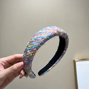 Close-up of a wide padded tweed headband featuring colorful woven texture in purple and blue