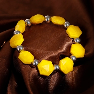 Macro shot of yellow marble-patterned resin beads with silver metal spacers on silk