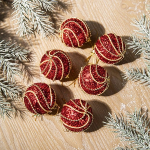 Set of 6 red glitter Christmas balls with golden beads on light wood background