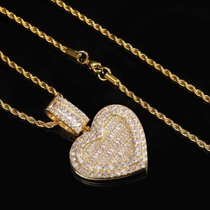 Close-up of gold iced-out heart photo pendant with cubic zirconia on twist rope chain