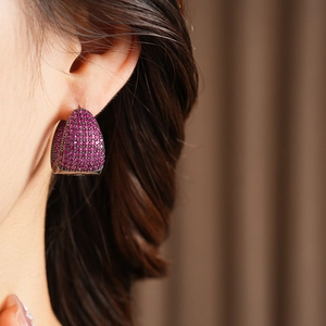 Close-up of elegant C-shaped hoop earrings with purple zircon crystals on model