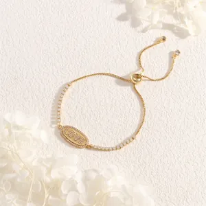 Detail of adjustable gold LOVE charm bracelet with sparkling zircons on stone background