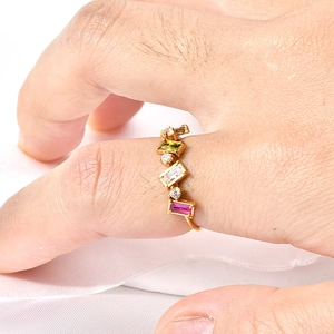 Vue détaillée d'une bague dorée ondulée avec gemmes colorées sur soie blanche