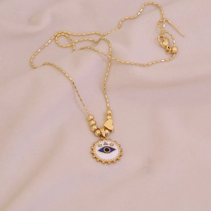 Golden bead chain necklace with evil eye pendant and heart charm on pink fabric