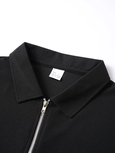 Close-up of black polo shirt collar with metal half-zipper and knit fabric texture