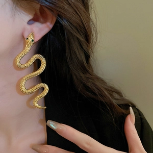 Exaggerated golden snake stud earrings with green rhinestones for a bold statement